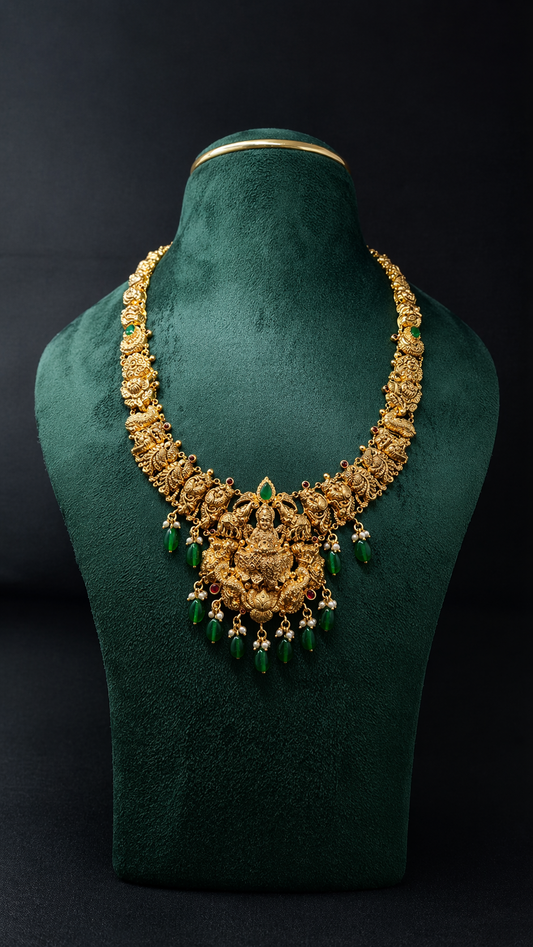 Handcrafted 22K Gold Gaja Lakshmi Temple Haram necklace with Nakshi detailing, elephant motifs, emerald green bead drops, and traditional South Indian bridal craftsmanship.