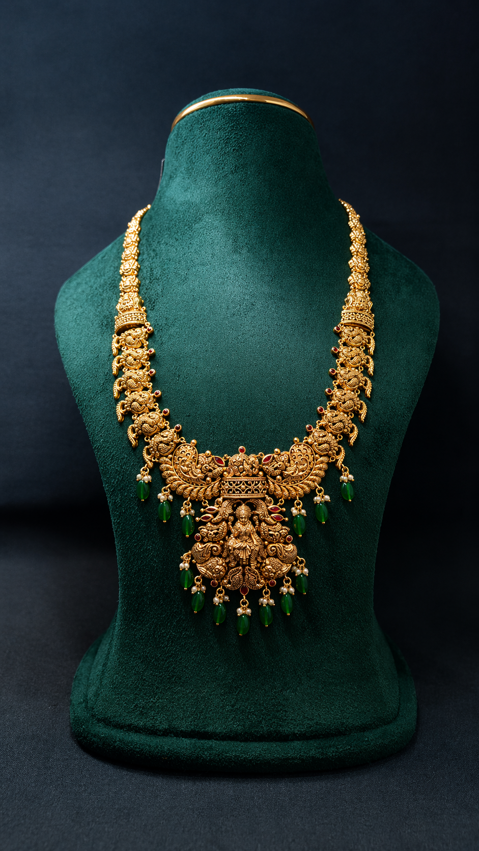 Handcrafted 22K Gold Lakshmi Peacock Temple Haram necklace with Nakshi detailing, emerald green bead drops, and traditional South Indian bridal craftsmanship.