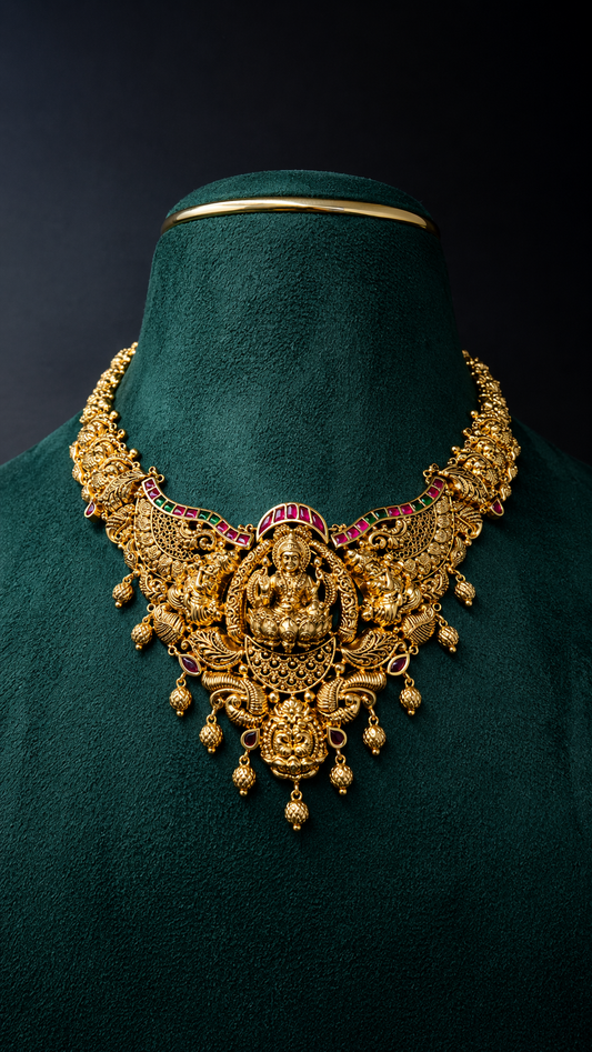 Lightweight 22K gold Lakshmi temple necklace with an ornate royal heritage pendant, decorative coloured accents, peacock motifs, and hanging gold bead details.