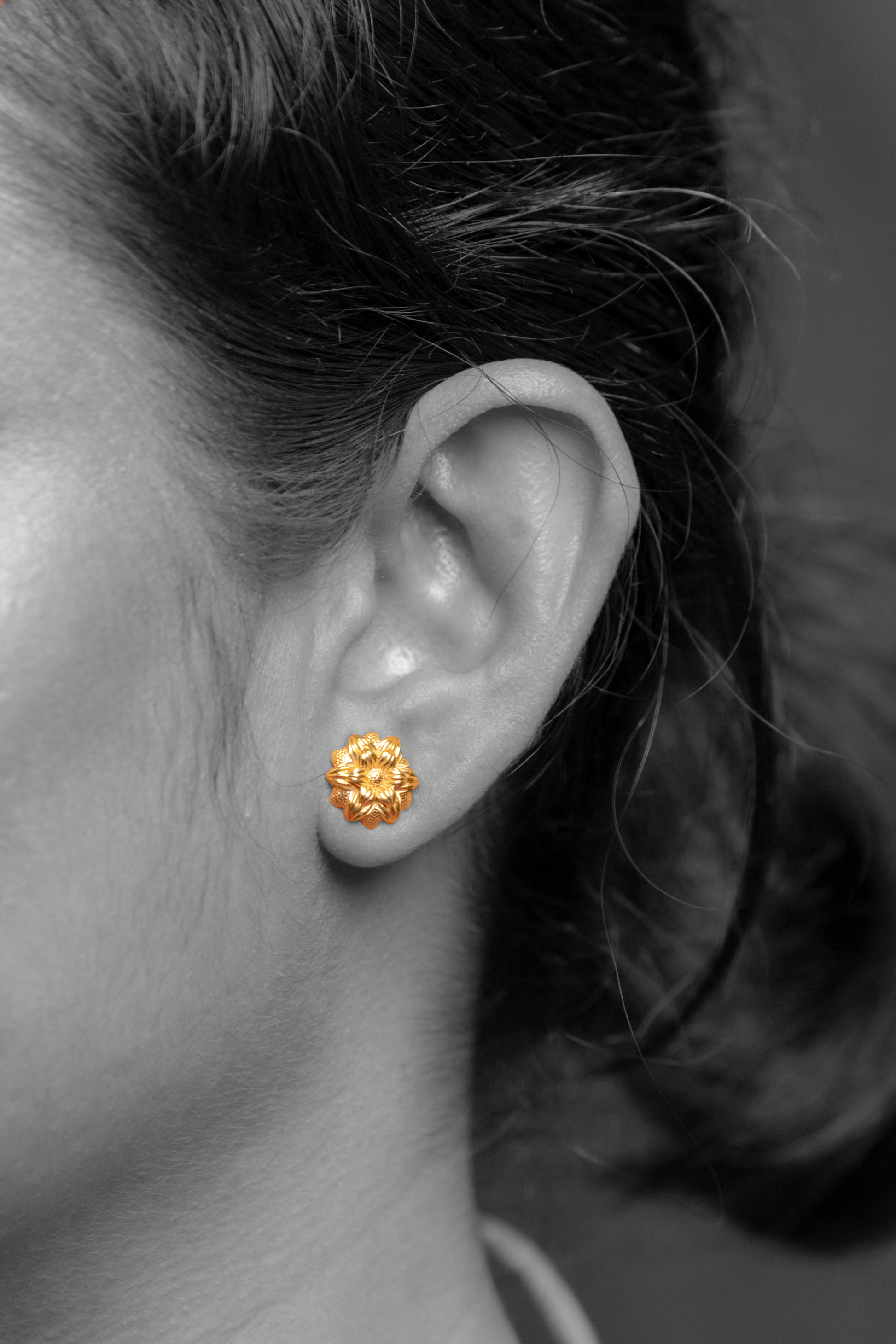 Model wearing Sculptyx Florent Hexa handcrafted 18K gold floral stud earrings.