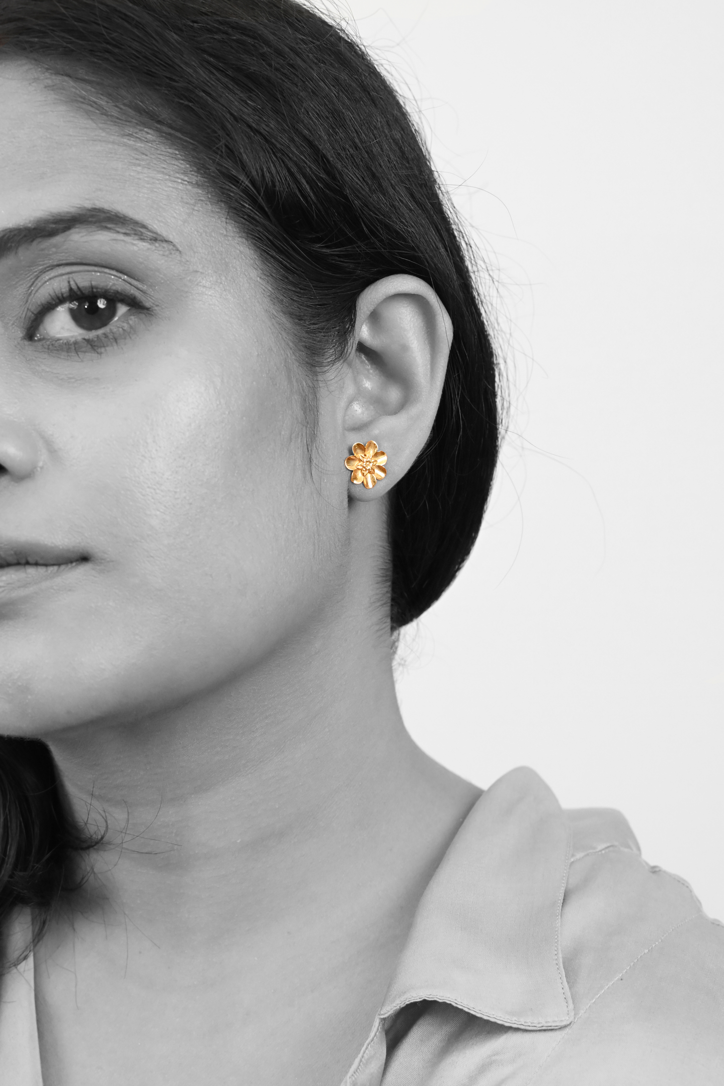 Model wearing Sculptyx Lunara Bloom handcrafted 18K gold floral stud earrings.
