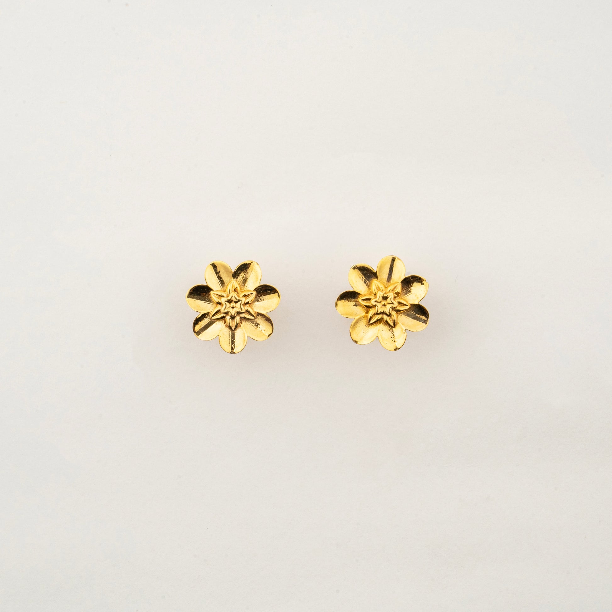 culptyx Lunara Bloom handcrafted 18K gold floral stud earrings featuring a delicate six-petal blossom design.