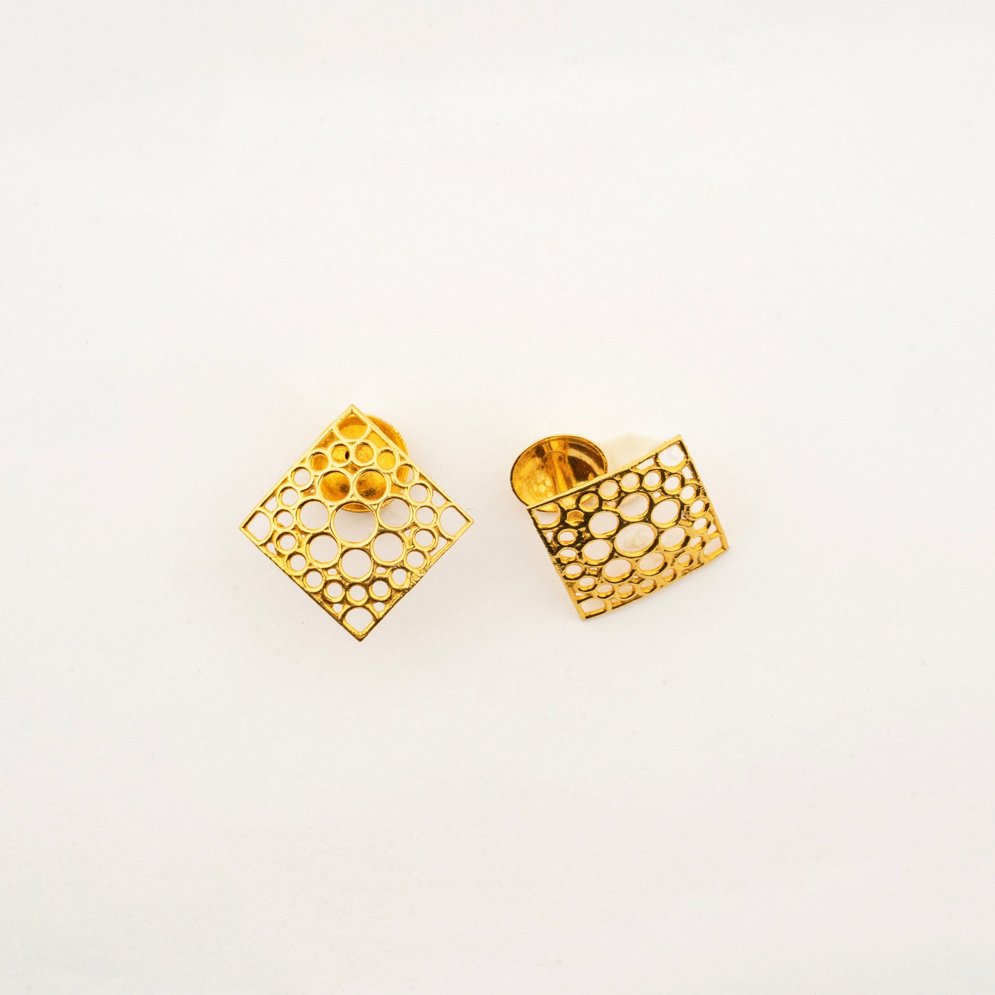 Close-up of Sculptyx Oculus Aurea 18K gold geometric stud earrings showcasing detailed openwork craftsmanship.