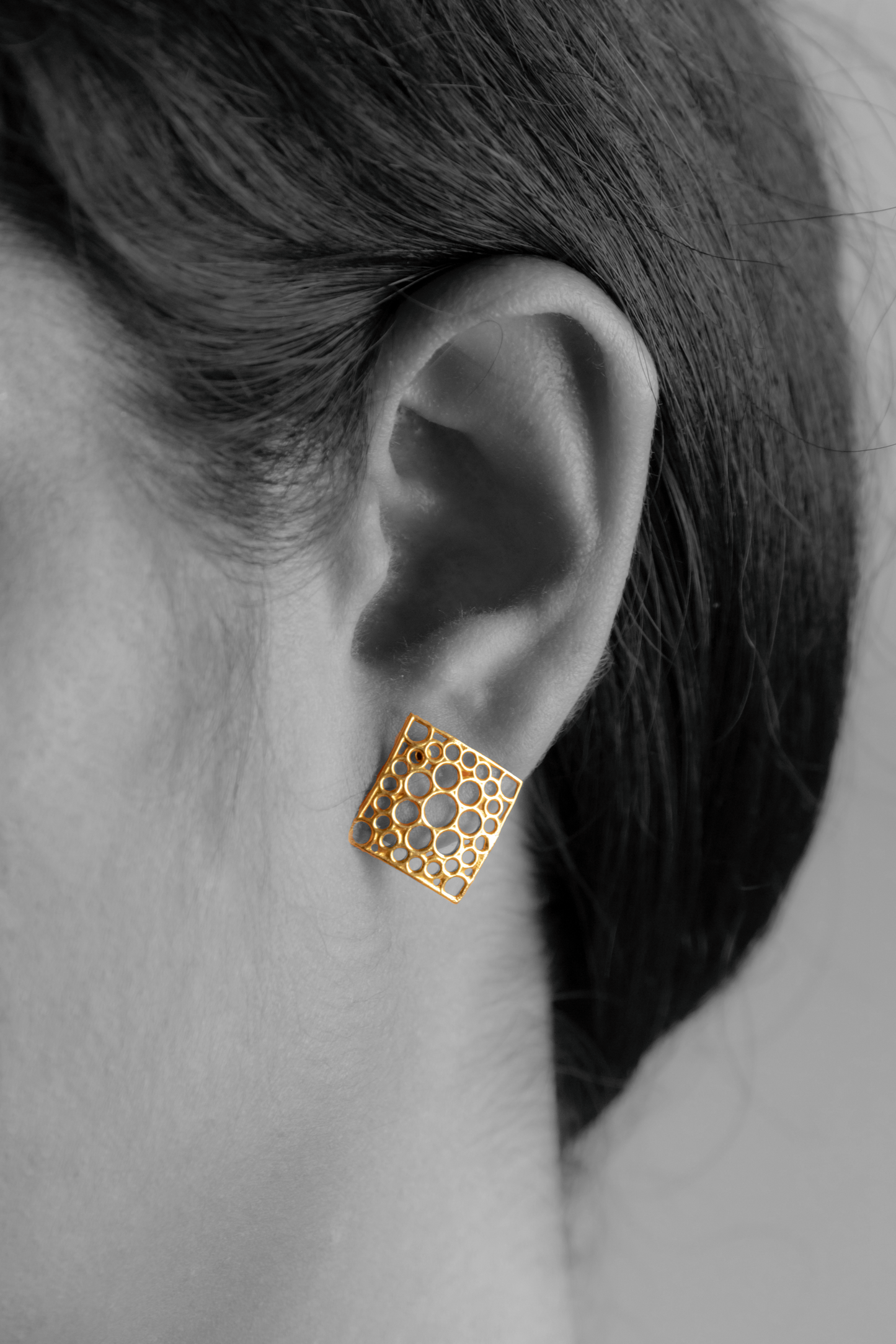 Model wearing Sculptyx Oculus Aurea handcrafted 18K gold geometric stud earrings.