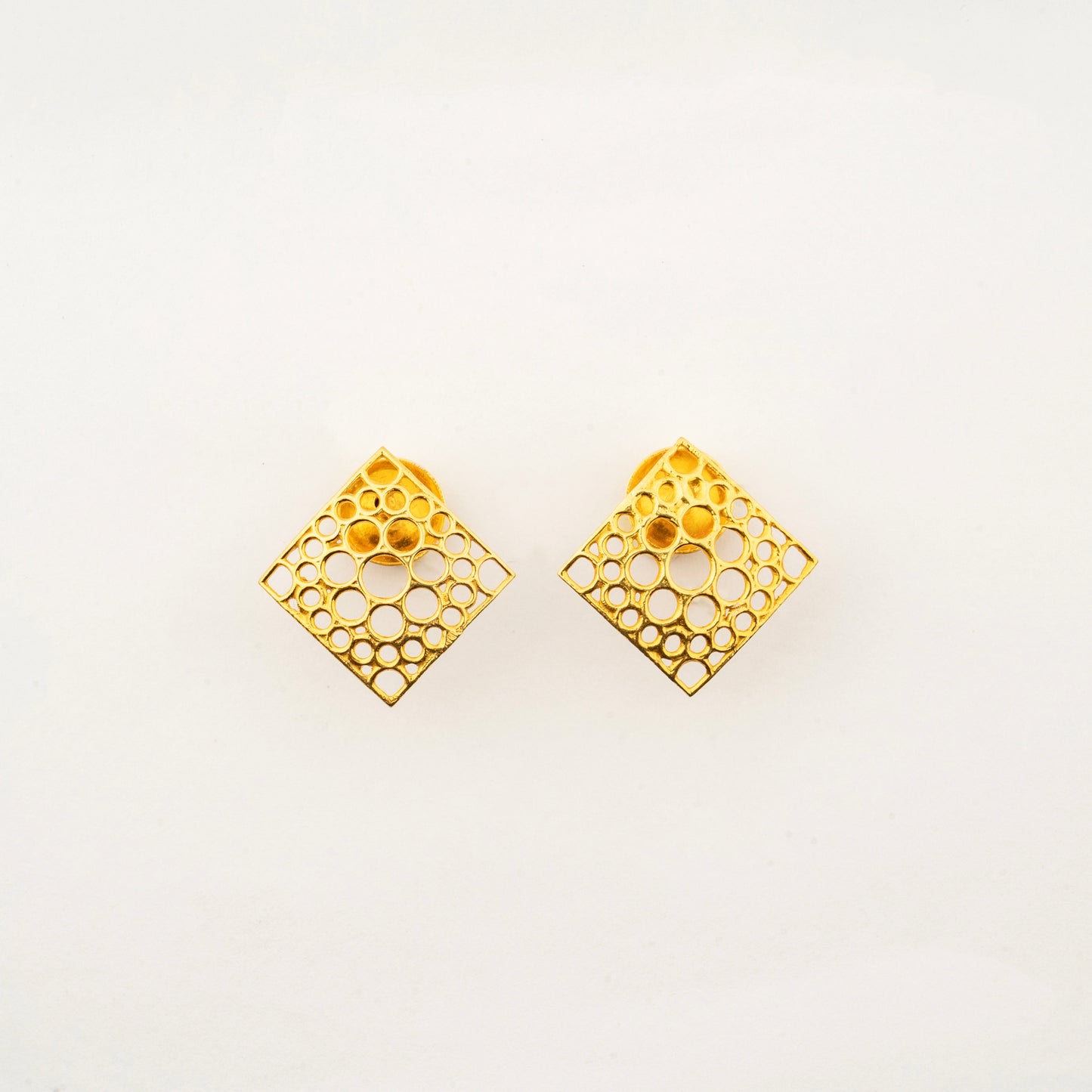 Sculptyx Oculus Aurea handcrafted 18K gold geometric stud earrings featuring an intricate openwork square design.