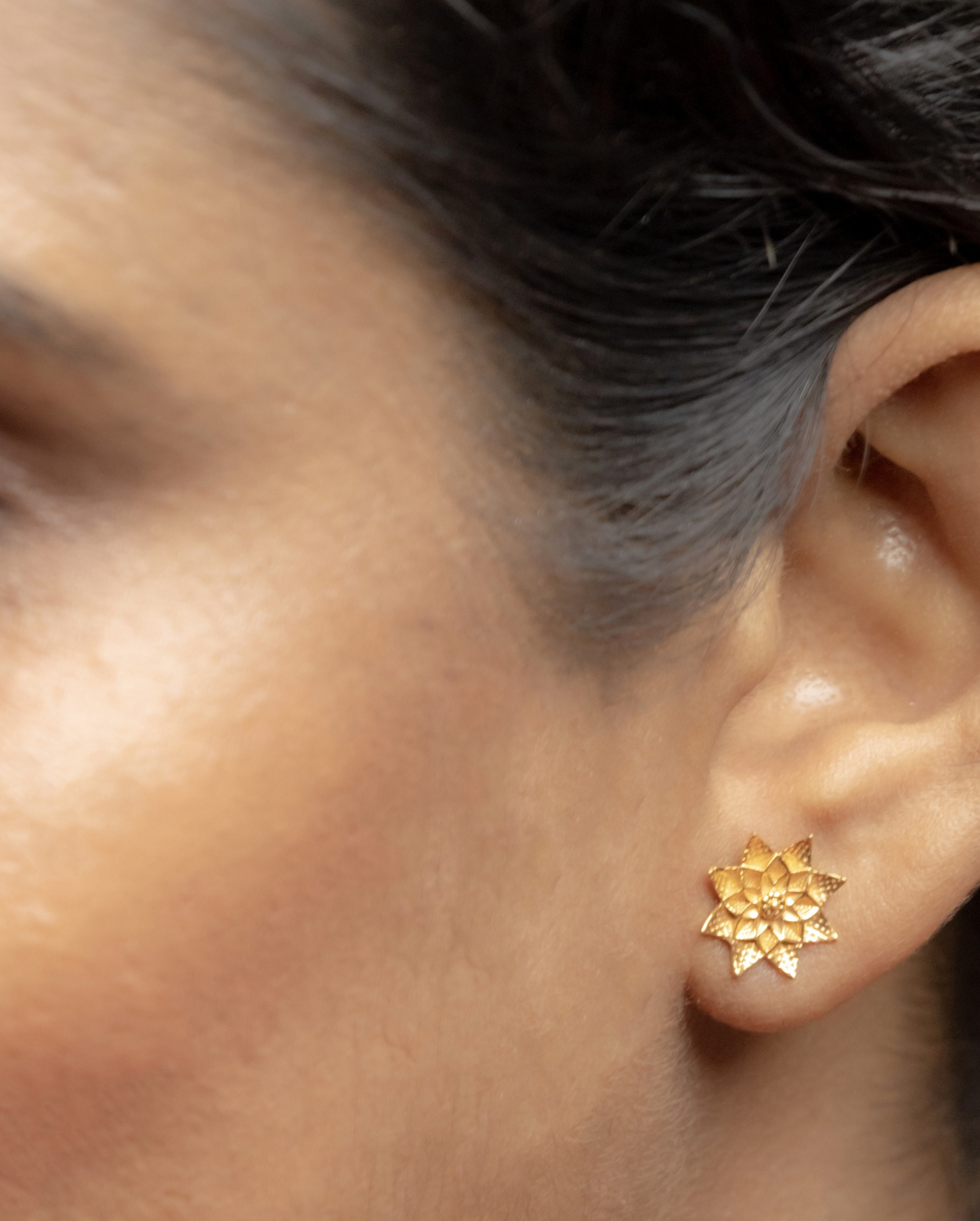 Model wearing Sculptyx Petralis Array handcrafted 18K gold botanical stud earrings.