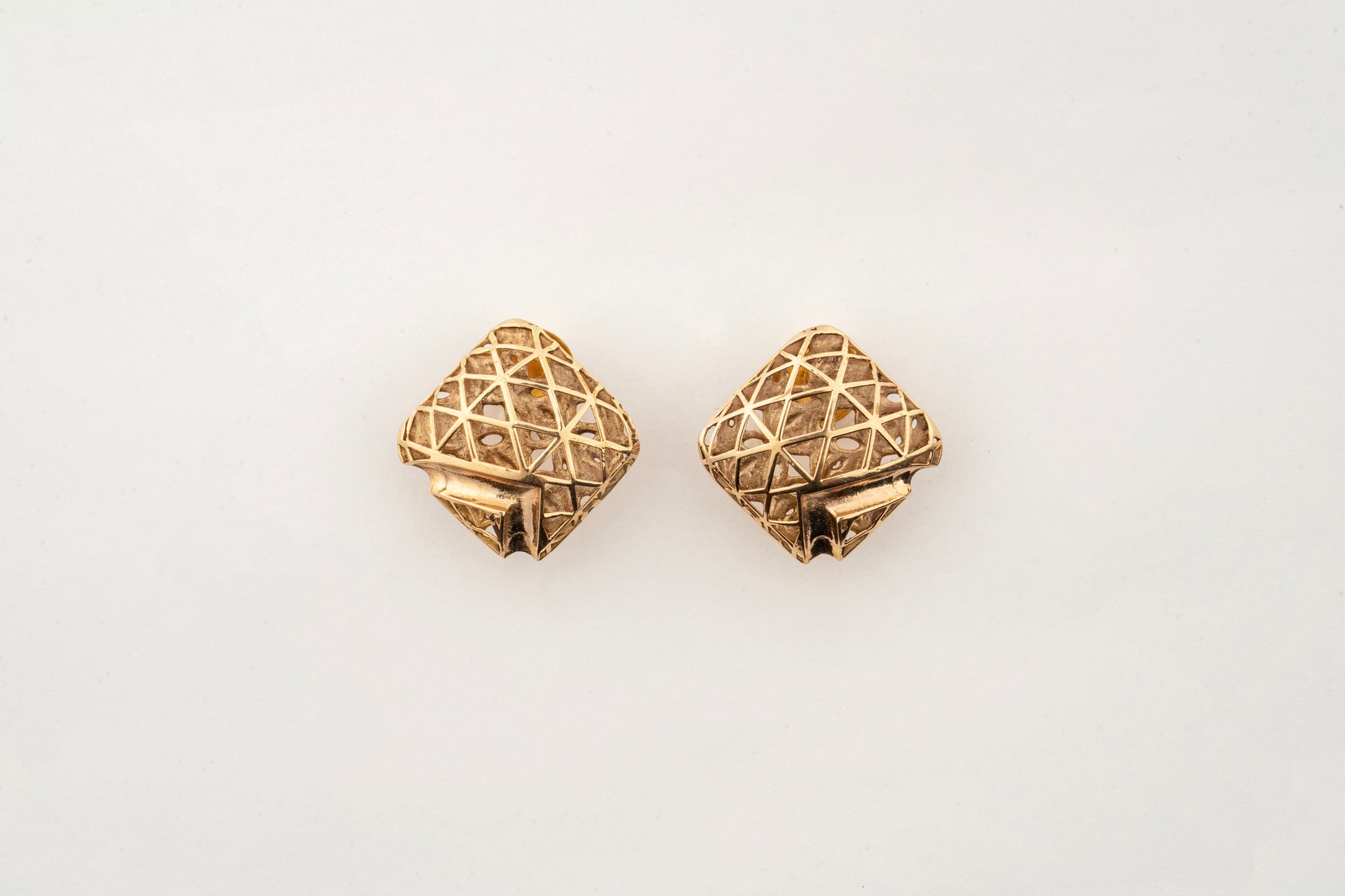 Close-up of Sculptyx Quadora Gridelle 18K gold geometric stud earrings showcasing precision handcrafted lattice detailing.