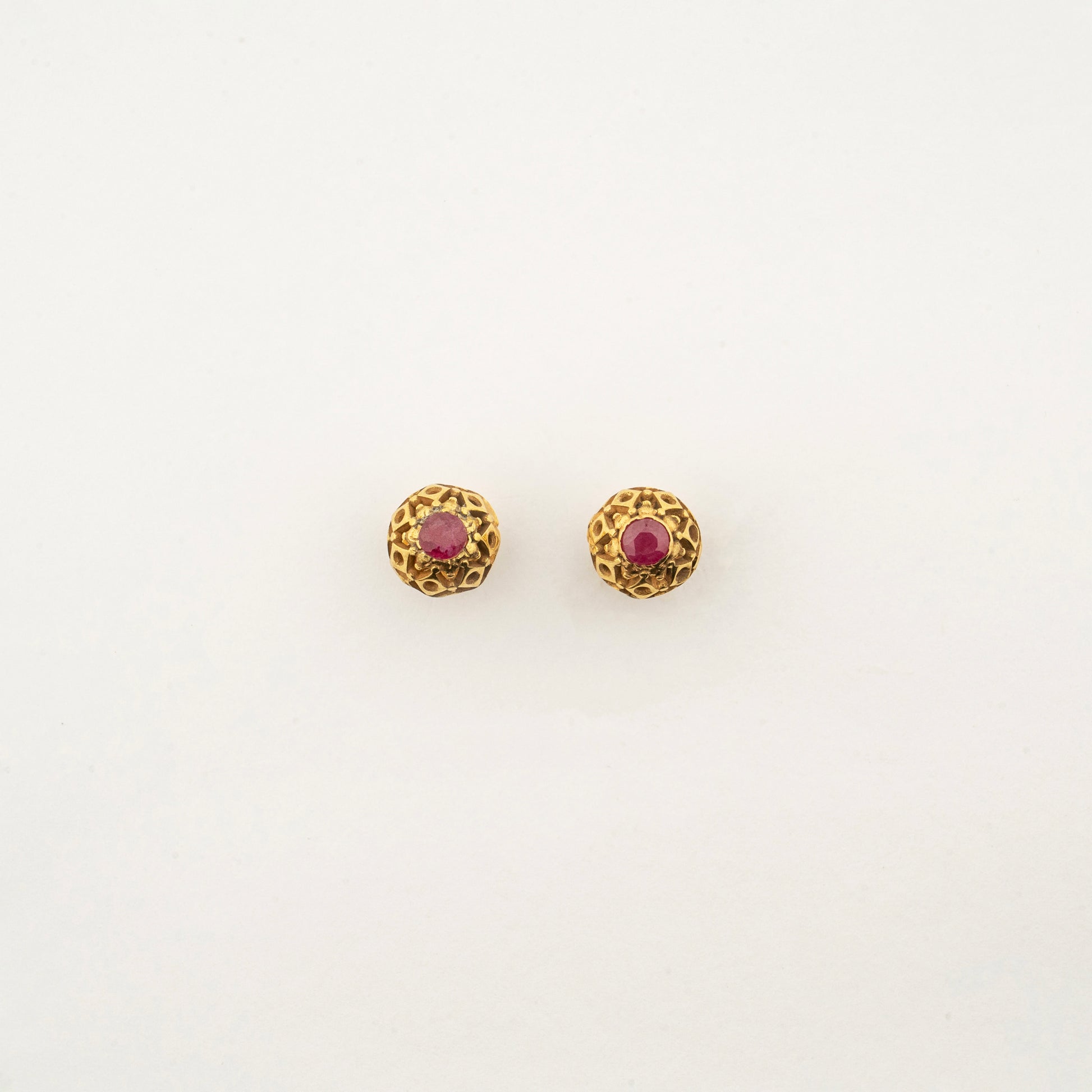 Sculptyx Ravikara handcrafted 18K gold ruby stud earrings featuring a textured antique-inspired gold setting with vibrant ruby gemstones.