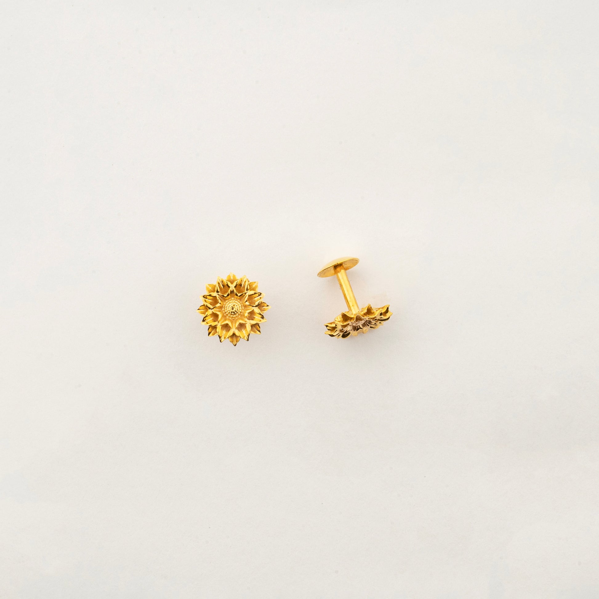 Close-up of Sculptyx Solaris Crest 18K gold stud earrings showcasing intricate handcrafted detailing.