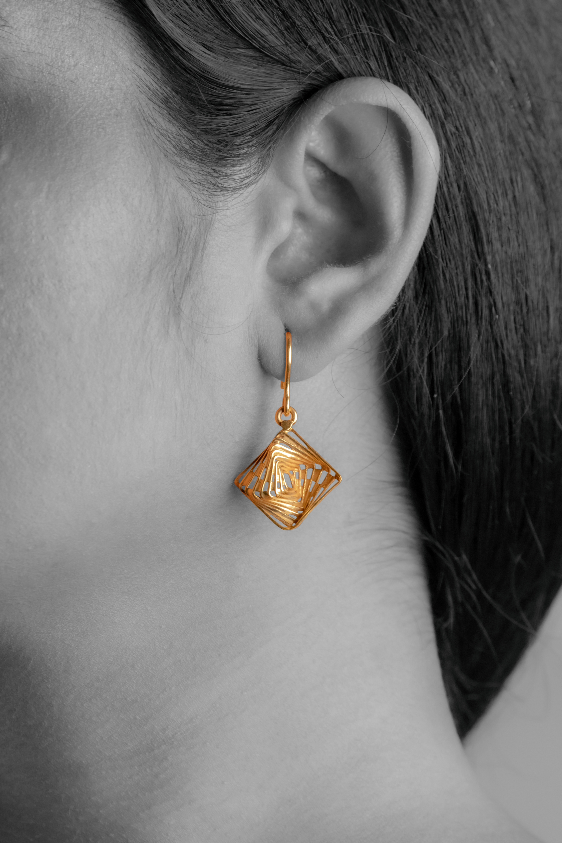 Model wearing Sculptyx The Golden Parallax handcrafted 18K gold geometric drop earrings.