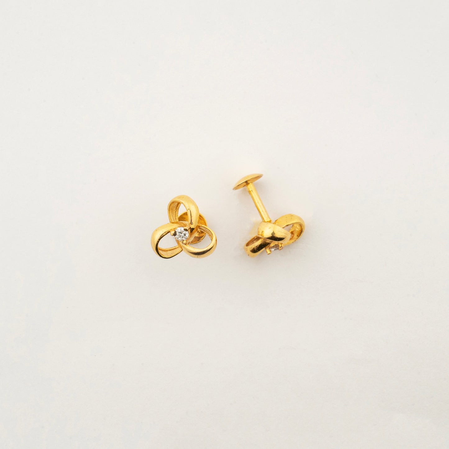 Sculptyx Tressara handcrafted 18K gold natural diamond stud earrings featuring elegant interlocking curves with a brilliant natural diamond centerpiece.