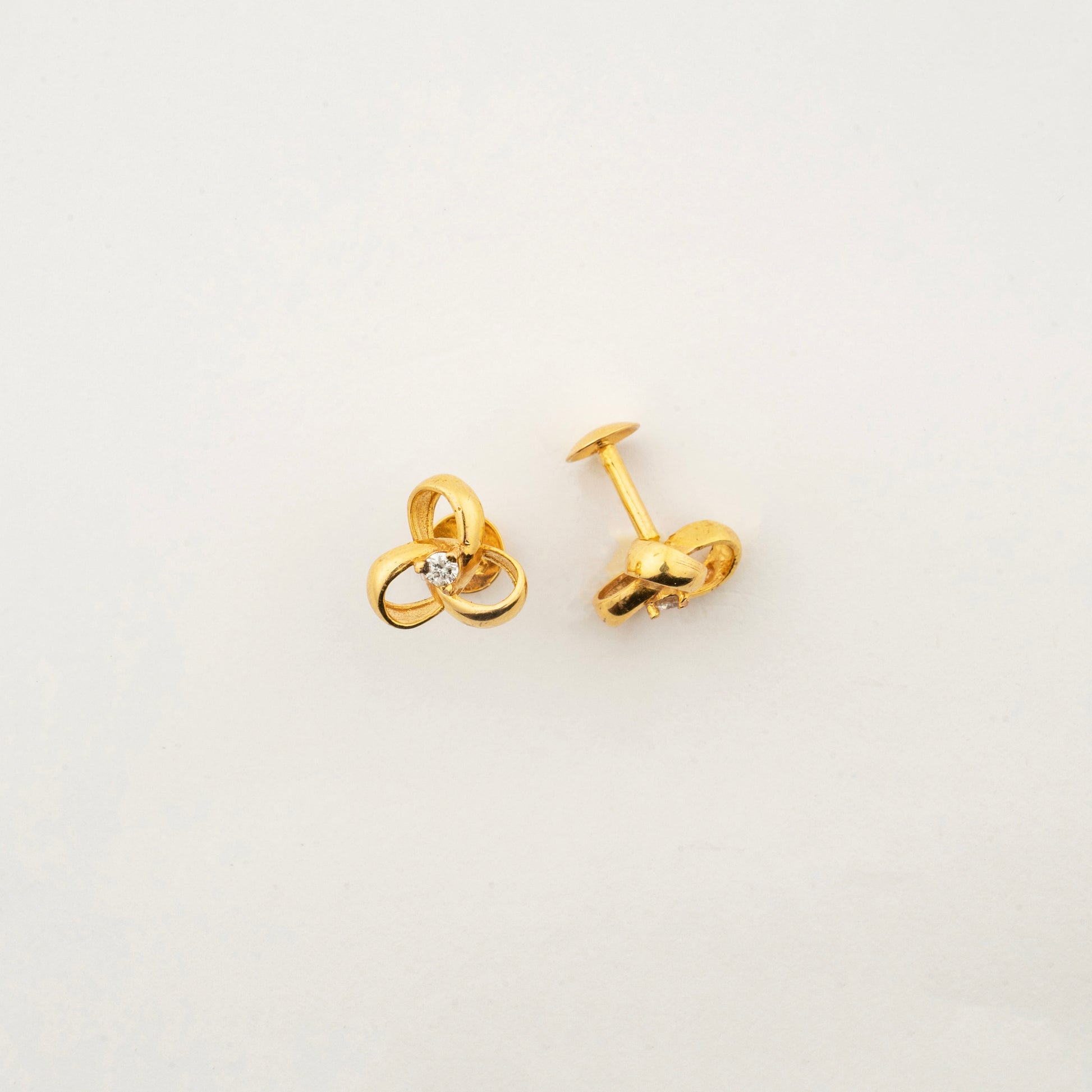 Sculptyx Tressara handcrafted 18K gold natural diamond stud earrings featuring elegant interlocking curves with a brilliant natural diamond centerpiece.