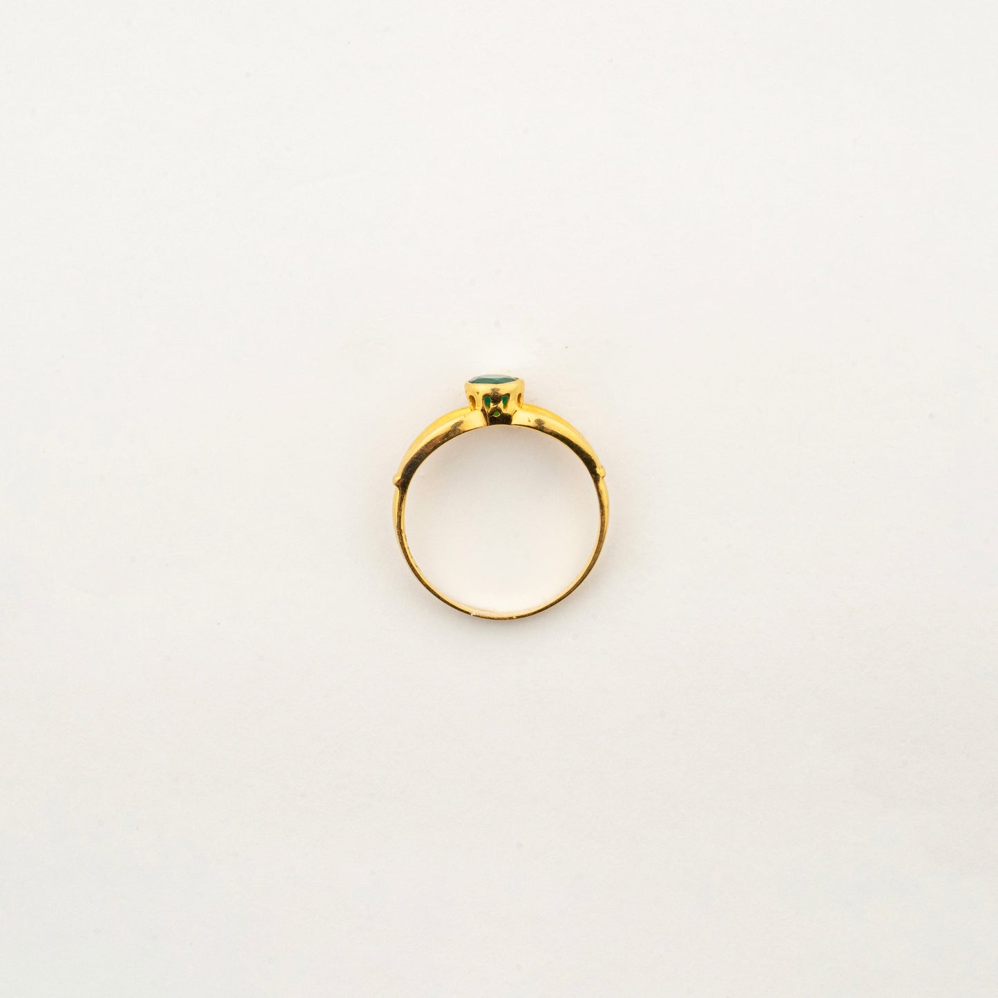 Top view of Sculptyx Verdant Axis 22K gold emerald ring showcasing its elegant handcrafted bezel setting.