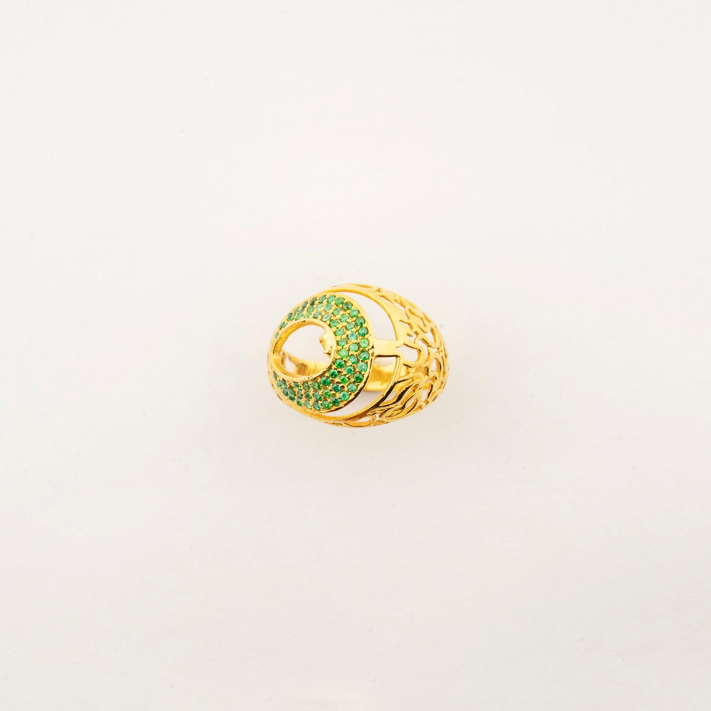 Sculptyx Vrideluna handcrafted 14K gold statement ring featuring a sculptural elliptical design accented with sparkling green crystals.